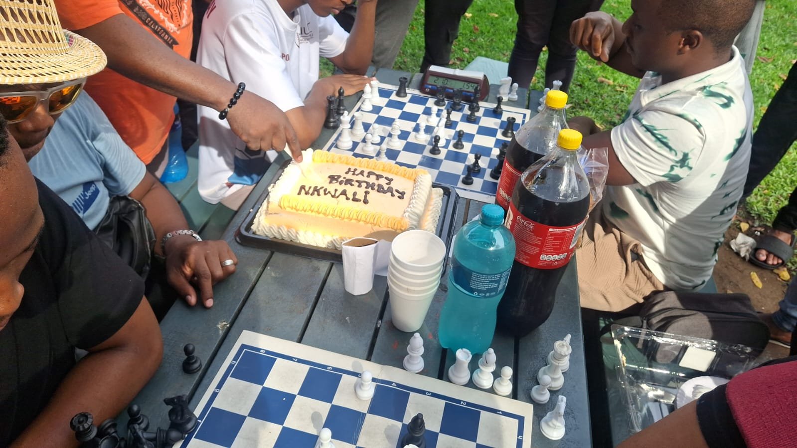 DMCA members sharing a birthday cake and chess games in the park
