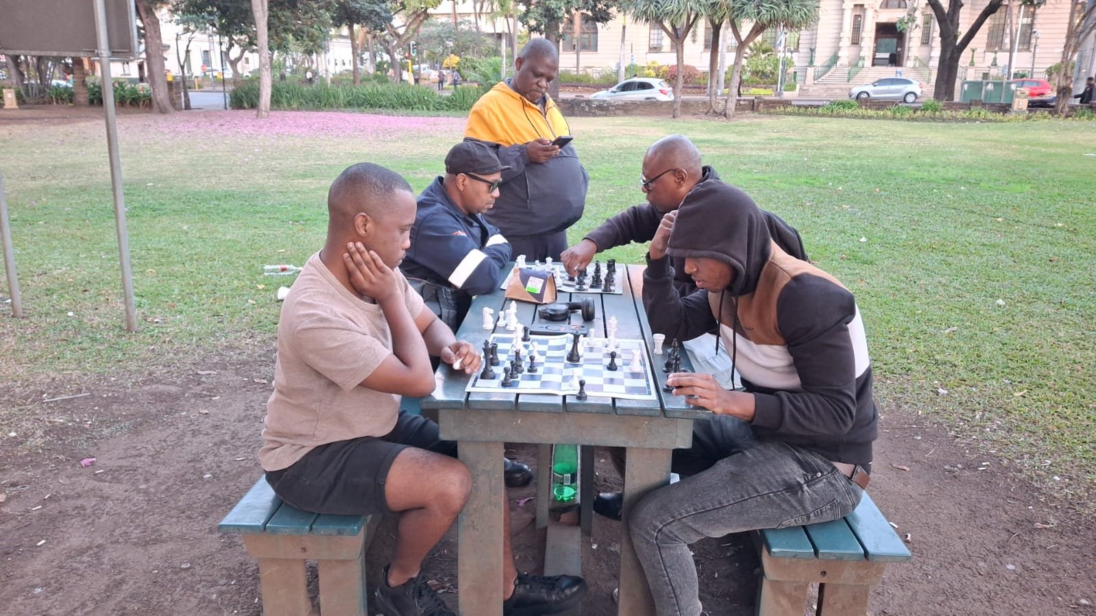 Chess players concentrating on their games at a picnic table in Medwood Gardens